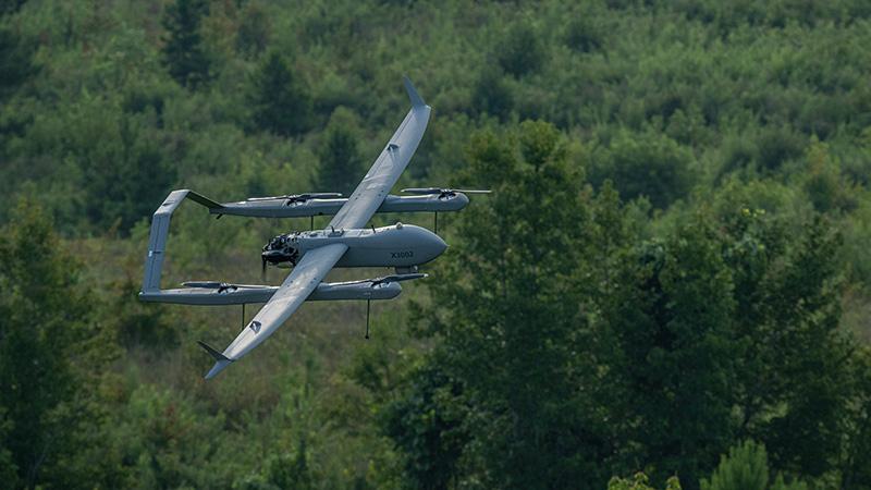 Aerosonde HQ in flight over forest